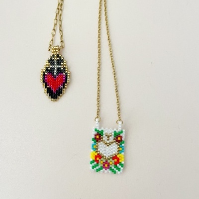 Dois colares com pendentes feitos de contas coloridas em padrões de coração e flores.