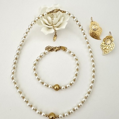 Conjunto de bijuteria com colar, pulseira de pérolas e brincos dourados sobre fundo branco