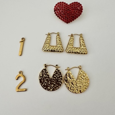 Peças de bijuteria douradas e coração vermelho com pedras brilhantes sobre fundo branco