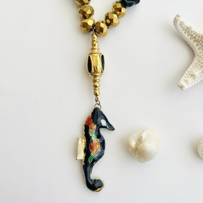 Colar com pendente de cavalo-marinho preto com detalhes florais em fundo branco