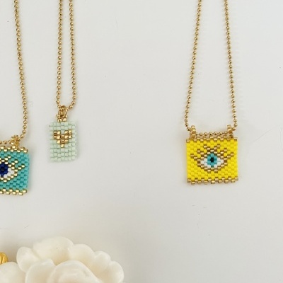 Colares com pendentes quadrados e retangulares coloridos feitos de contas sobre fundo branco.