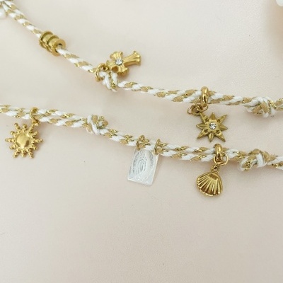 Colares com símbolos dourados pendurados em fios brancos entrelaçados com dourado