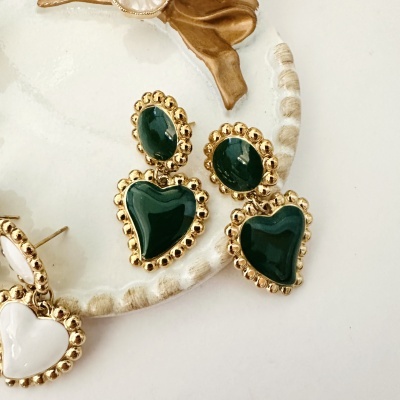 Brincos de coração verde com moldura dourada em prato branco decorativo