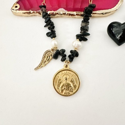 Colar com medalha dourada ST RAPHAEL, pedras pretas, pérolas e pendente de asa com brilhantes, ao lado de estojo vermelho e coração preto