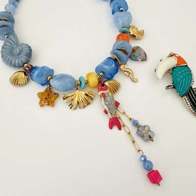 Colar azul com pendentes dourados e peixe colorido, e broche de papagaio colorido
