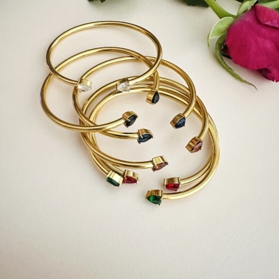 Pulseiras douradas com pedras coloridas e flor rosa