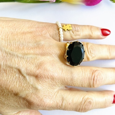 Mão feminina com anéis e flores cor de rosa e amarelas ao fundo