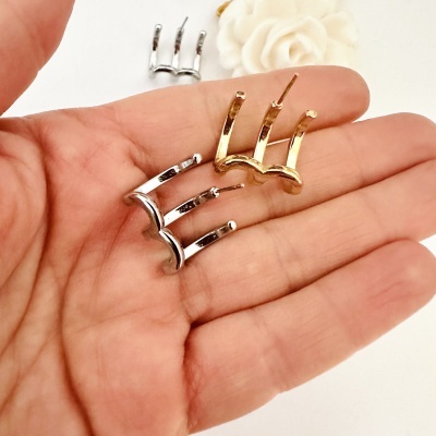 Brincos de metal dourado e prateado com três garras na mão