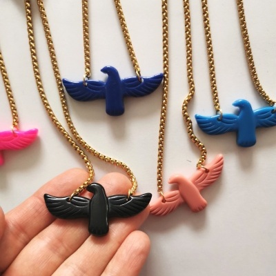 Colares com pendentes de pássaros coloridos em correntes douradas sobre fundo branco