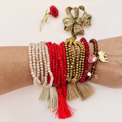 Pulseras coloridas com contas e pendentes dourados num braço