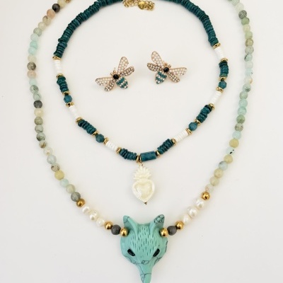 Conjunto de dois colares com pendentes e brincos em forma de abelha sobre fundo branco