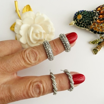 Quatro brincos de argola em metal prateado, dois com strass e dois texturizados, com decoração de flor e pássaro.