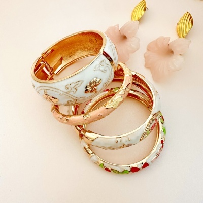 Pulseiras douradas esmaltadas e brincos com flores rosadas