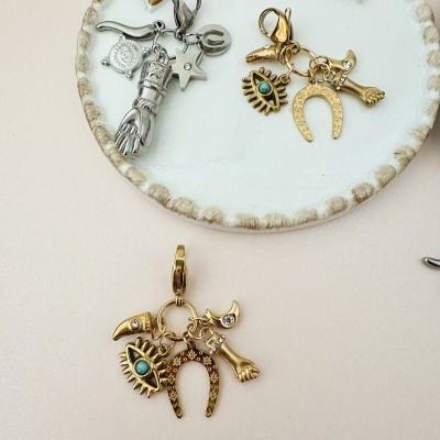 Conjuntos de pingentes metálicos dourados e prateados com formas variadas sobre um prato branco