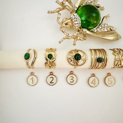 anel dourado com pedra verde e broche dourado com pedra verde