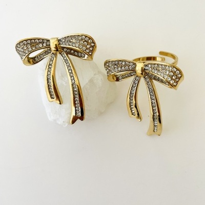 Anéis dourados com laço e pedras brilhantes sobre fundo branco