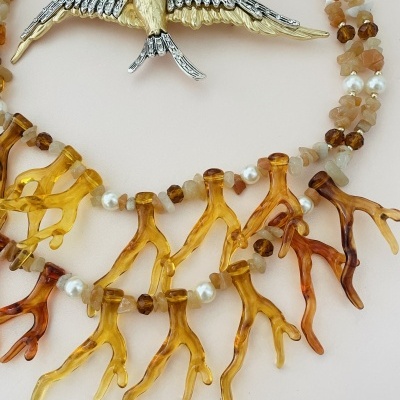 Colar com contas castanho-âmbar, pérolas brancas e pendentes em forma de galhos dourados com um pendente de pássaro dourado e prateado