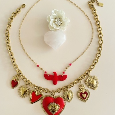 colar com pendentes em forma de corações vermelhos e dourados, colar com pendente pá vermelho e anel branco com flor e coração
