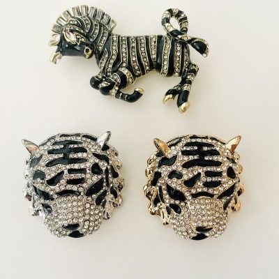 Três broches animais em preto, prata e dourado com strass sobre fundo branco