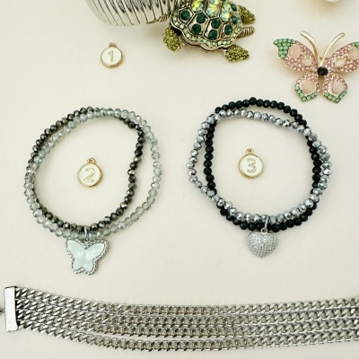 Dois conjuntos de pulseiras com pingentes de borboleta e coração, alfinetes decorativos e pulseira metálica prateada