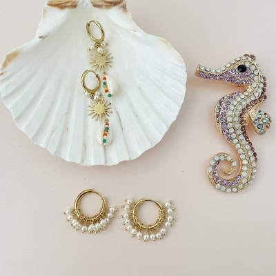 Brincos dourados com pérolas e concha, broche de cavalo-marinho com strass numa concha branca