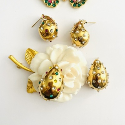 Conjunto de bijuteria dourado com pedra coloridas e broche flor branca