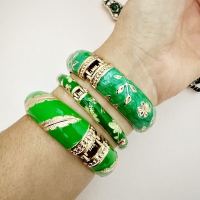 Pulseiras rígidas verdes com detalhes dourados no pulso