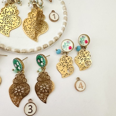 Brincos dourados com detalhes florais e etiquetas numeradas