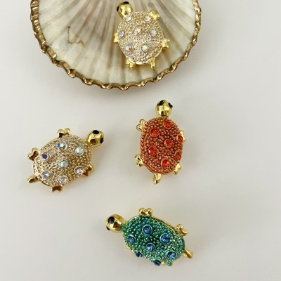 Pendentes de tartaruga coloridos com brilhantes sobre uma concha com borda dourada