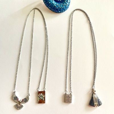 Colares prateados com diferentes pendentes sobre fundo branco e adorno azul em forma de concha