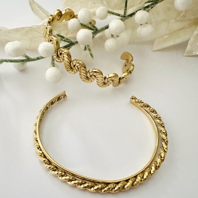 Braceletes dourados com padrões texturizados em superfície branca decorada