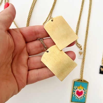 Colares com pendentes de metal e coloridos sobre fundo branco
