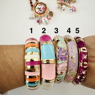 Cinco pulseiras coloridas e esmaltadas numeradas, vistas num braço.