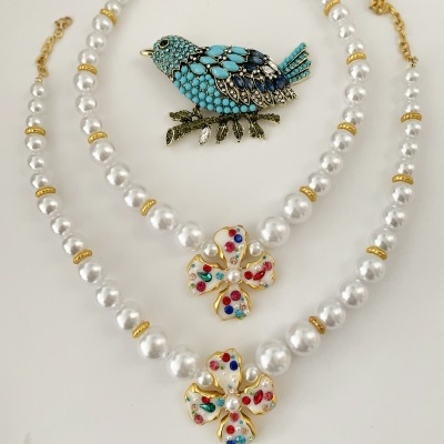 Colares de pérolas com flores coloridas e broche de pássaro azul