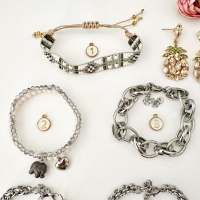 Três pulseiras numeradas com diferentes materiais e padrões sobre fundo branco