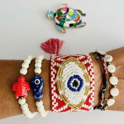 Pulseiras coloridas com contas e broche de tartaruga sobre fundo branco