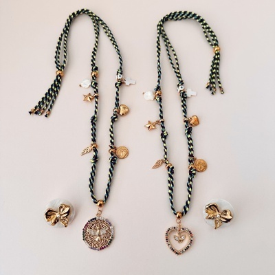 Duas gargantilhas trançadas azuis e verdes com pendentes dourados e brincos dourados de laço.