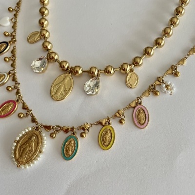 Três colares dourados com medalhas religiosas coloridas e detalhes em pérolas e flores pequenas