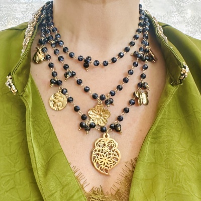 Colar de várias camadas com contas negras e pendentes dourados em forma de borboleta e flores