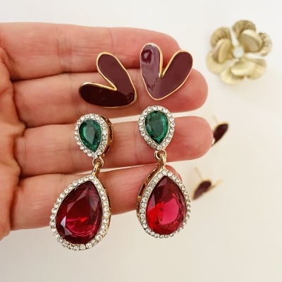 Brincos com pedras verdes e vermelhas em forma de gota com moldura de cristais e base dourada.