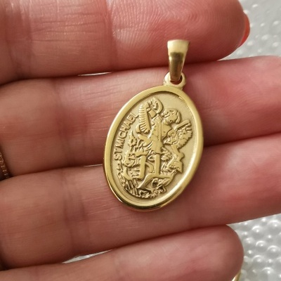 Pingente oval dourado de São Miguel Arcanjo em mão