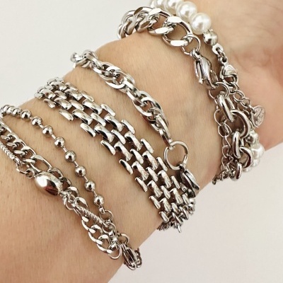 Pulseiras de metal prateado e pérolas brancas num braço