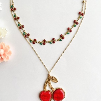Colar duplo dourado com pendente de cerejas vermelhas e detalhes verdes