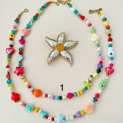 Colares coloridos com contas em várias formas e broche em forma de flor sobre fundo bege