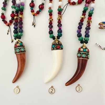 Três colares com pendentes em forma de presa e contas coloridas numerados 1, 2 e 3.