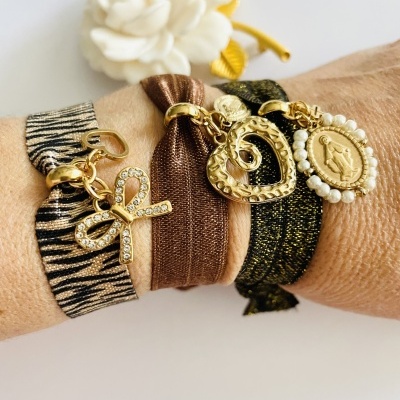 Pulseiras elásticas com pendentes dourados e padrão zebra, castanho e preto no pulso esquerdo