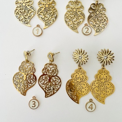 Quatro pares de brincos dourados com design recortado e pendentes em forma de coração sobre fundo branco