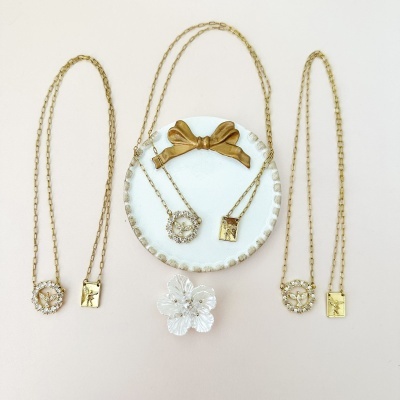 Colares dourados com medalhas e broche flor branca