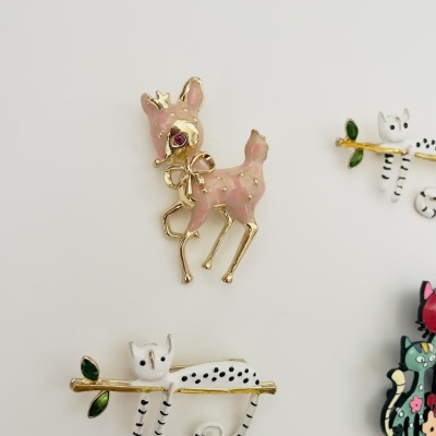 Brincos esmaltados em metal dourado com desenhos de cervo e gatos, sobre fundo branco.