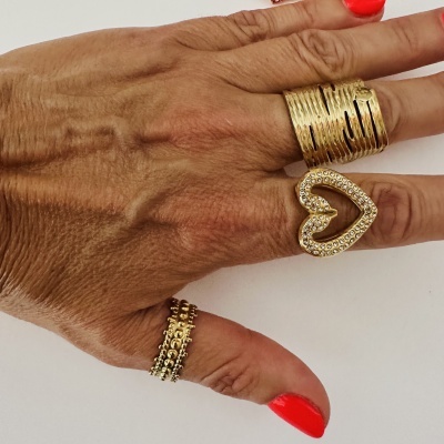 Três anéis dourados em mão com unhas vermelhas, fundo branco.